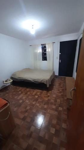 een slaapkamer met een bed en een houten vloer bij Apartamento Cosquin a metros del centro in Cosquín