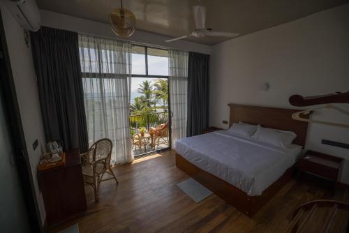 a bedroom with a bed and a large window at Surftunnel Beach Resort in Weligama