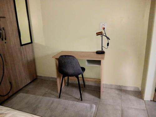 a desk with a chair and a lamp in a room at The Corner Nest in Roodepoort