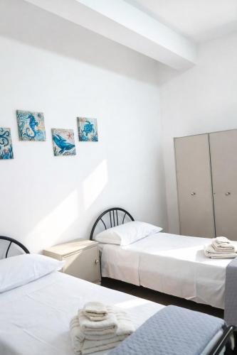 two beds in a room with white walls at CasaTreFontane in Bovalino Marina