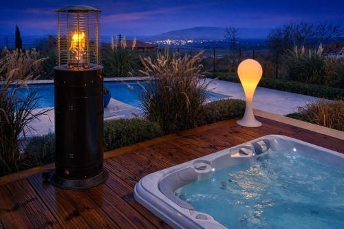 a jacuzzi tub on a wooden deck with a light at Villa Aura Heated Pool&Jacuzzi near Albena in Rogachevo