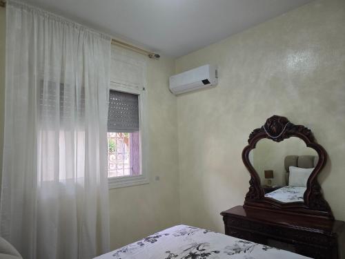 een slaapkamer met een spiegel, een bed en een raam bij Appartement meublé in Meknès
