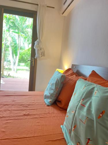 a bedroom with a bed with orange sheets and a window at Thelazycoco in Blue Bay