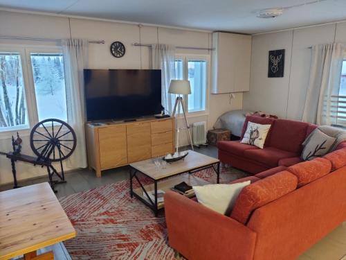 een woonkamer met een bank en een flatscreen-tv bij Einon Tupa in Kittilä