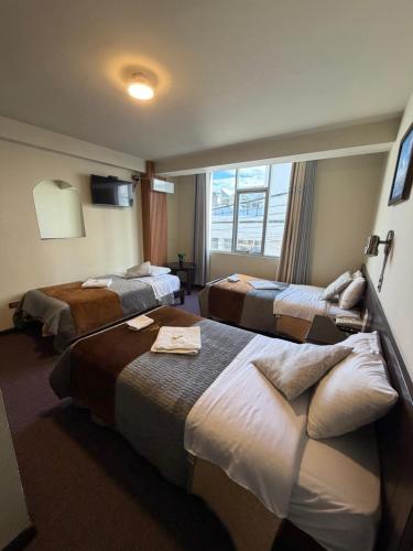 een hotelkamer met 3 bedden en een raam bij Camino Real Puno in Puno