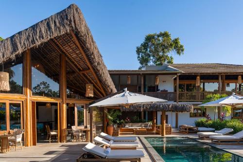 a resort with a swimming pool and lounge chairs and umbrellas at Aketá Hotel Boutique in Trancoso