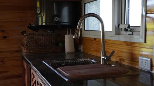 a kitchen sink with a wooden cutting board in it at La Loica in El Maitén