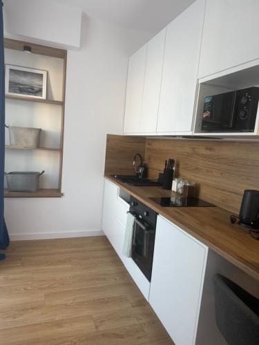 a kitchen with white cabinets and a wooden counter top at MW 4A Apartament in Rzeszów