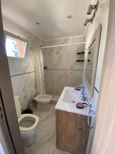 a bathroom with a sink and a toilet and a mirror at FloreSer in Villa Gesell