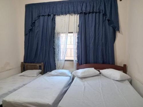 two twin beds in a room with a window at Aconchego de mae - 5 min do Santuário e comércios - Casa completa in Aparecida