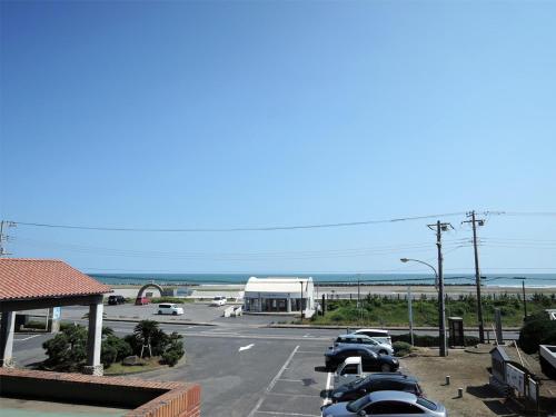 a parking lot with cars parked next to the ocean at Iioka Shiosai Hotel in Asahi