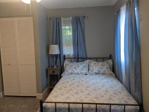a bedroom with a bed with blue curtains and a window at Cottage & Garden in Jacksonville