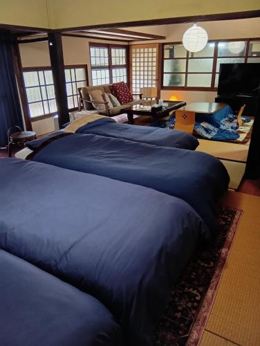 a bedroom with four blue beds and a living room at 横城ゲストハウス 自然豊かなプライベート空間 古民家一棟貸しの宿 in Kitsuki