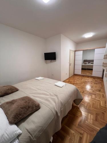 a white bedroom with a large bed and a flat screen tv at Apartman Luka in Cetinje