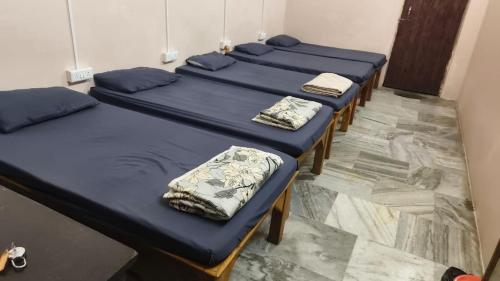 een rij bedden in een kamer met blauwe lakens bij 5 Star Yatri Vishram Dormitory & Rooms in Jabalpur