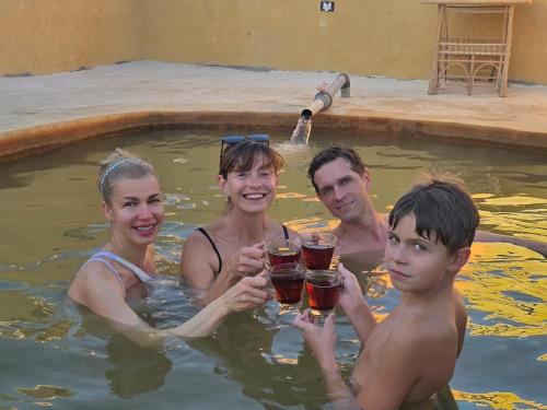 Eine Gruppe von Menschen trinkt Bier in einem Schwimmbad in der Unterkunft Papy house in Siwa