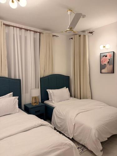 a bedroom with two beds and a ceiling fan at Kijani Luxury Beach apartment in Malindi