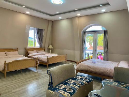 a bedroom with two beds and a chair and a window at Sa Villa Da Lat in Da Lat