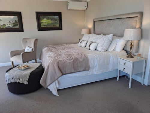 a bedroom with a white bed and a chair at Boutique Inn - Serenity in Gordonʼs Bay
