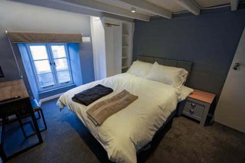a bedroom with a bed with white sheets and a window at Monk and Tipster in Towcester