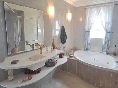 a bathroom with a sink and a tub and a mirror at Boutique Inn - Serenity in Gordonʼs Bay