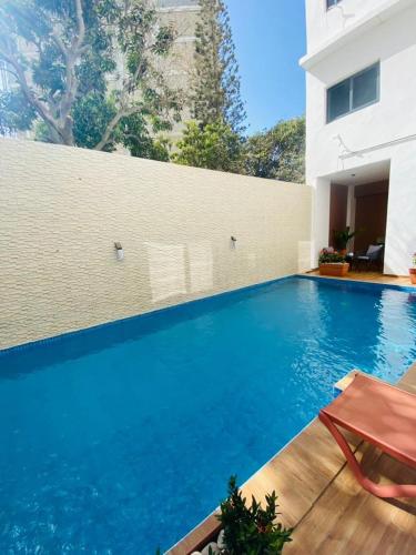 a large swimming pool with blue water in front of a building at Sélénite in Dakan