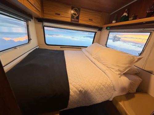 a bed in the middle of a room with two windows at Camper Elegance Uyuni - All Inclusive in Carpas