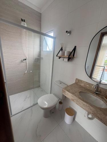 a bathroom with a toilet and a shower and a sink at Casa beira Mar in Itanhaém