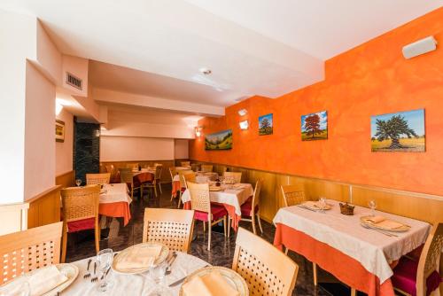 a restaurant with tables and chairs and orange walls at Hotel Au Soleil in Saint Vincent