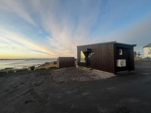a house on the beach with the ocean in the background at Unik og moderne microhytte med utsikt mot havet 40 A Otterlei Resort in Longva