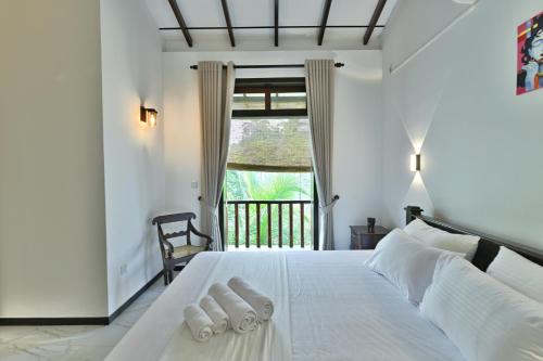 a bedroom with a white bed with two towels on it at Mansion view in Unawatuna