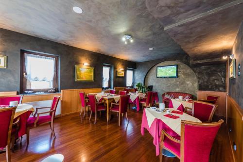 a restaurant with tables and red chairs in a room at Hotel Au Soleil in Saint Vincent