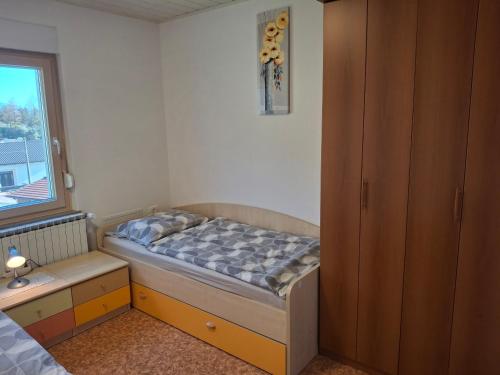a small bedroom with a bed and a window at Apartma Jasen in Ilirska Bistrica