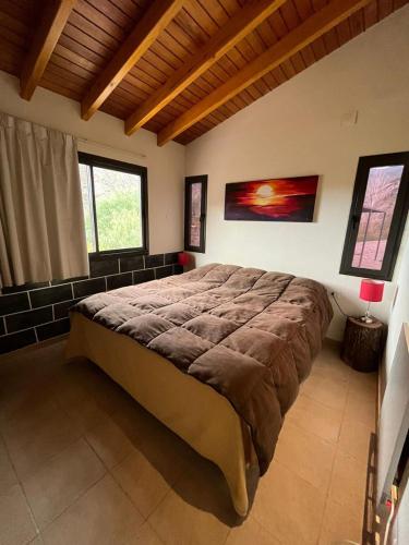 a bedroom with a large bed in a room with windows at Cabaña en Barrio Privado de Potrerillos in Potrerillos