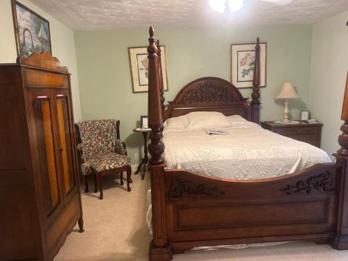 a bedroom with a wooden bed and a chair at serenity hill in Brownsville