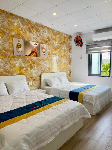 a bedroom with two beds and a wall mural at Ruby Hotel in Nhơn Trạch