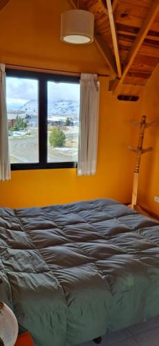 a bed in a room with a large window at Patagonia Adriano in Caviahue