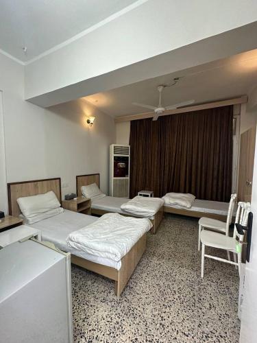 a room with three beds and a table and chairs at فندق حمورابي Hammurabi Hotel in An Nāşirīyah