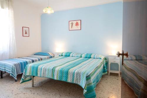 two beds in a bedroom with blue walls at Marcelli, trilocale con balcone e posto auto in Marcelli