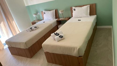 a room with two beds with white sheets at Urban Hostel Mindelo in Mindelo