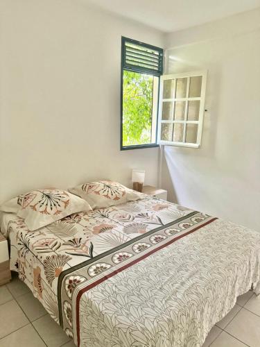 a bed in a bedroom with a window at Repaire des Alizés in Le Moule