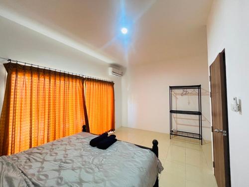 ein Schlafzimmer mit einem Bett mit einem orangenen Vorhang in der Unterkunft Winlee house in Ban Phlu Yai