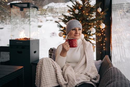 een vrouw die in een stoel zit met een kop koffie bij Domek Pierwiosnek Ustroń - cisza, las, balia i totalny relaks - Ucieknij od zgiełku i poczuj spokój natury in Ustroń