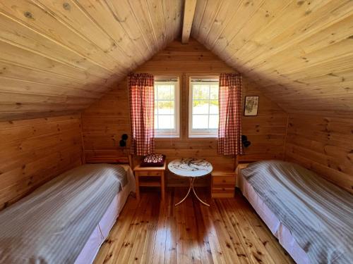 two beds in a log cabin with a table at Øen Hytter - Hytte 2 in Sørbø