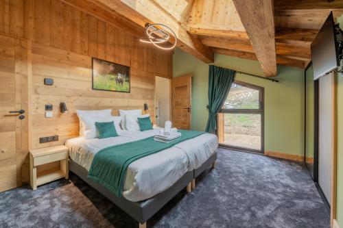 a bedroom with a large bed and a window at Chalet APY - Grand chalet neuf avec terrasse, 6 chambres en-suite , wifi, balcon, etc in Les Gets
