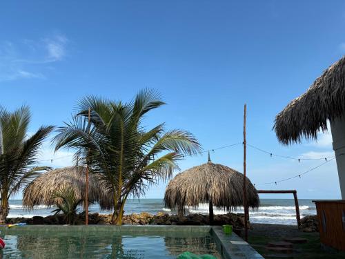 a resort with a swimming pool and palm trees on the beach at Cosamui Beach House in San Bernardo del Viento
