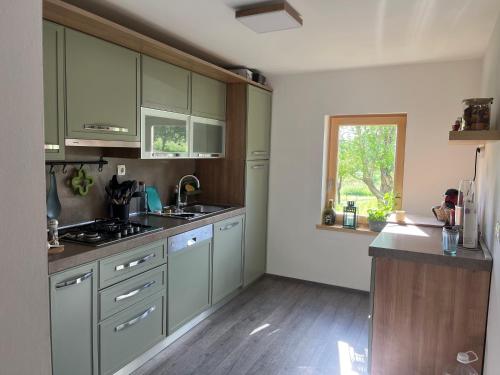 eine Küche mit grünen Schränken und einem Fenster in der Unterkunft Green House kuća s 4 spavaće sobe in Stara Sušica