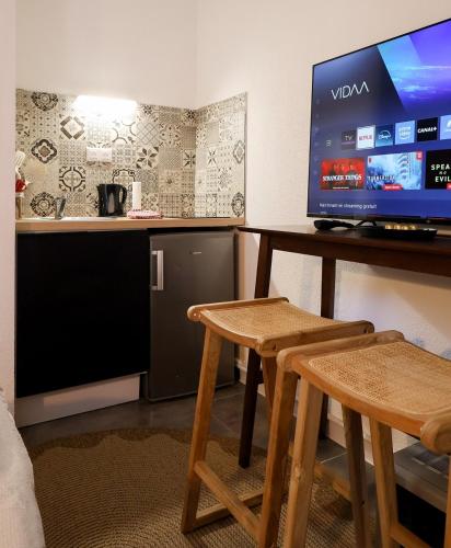un salon avec une télévision sur une table avec des tabourets dans l'établissement Studio tropical, au Puy-en-Velay