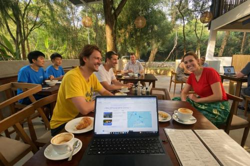 a group of people sitting at a table with a laptop at Jungle Trails in Sigiriya