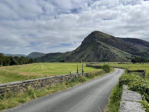 a dirt road with a mountain in the distance at Y Mor Cosy Apartment in Tywyn